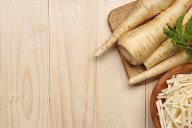 Photo of Whole and cut fresh ripe parsnips on wooden table, flat lay. Space for text