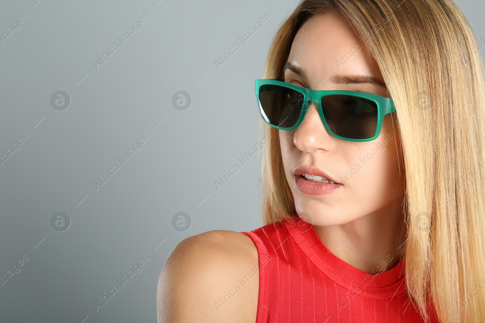 Photo of Beautiful woman in stylish sunglasses on grey background, closeup. Space for text