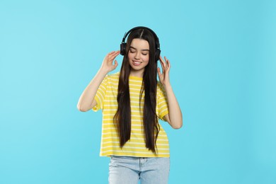 Photo of Teenage girl listening music with headphones on light blue background