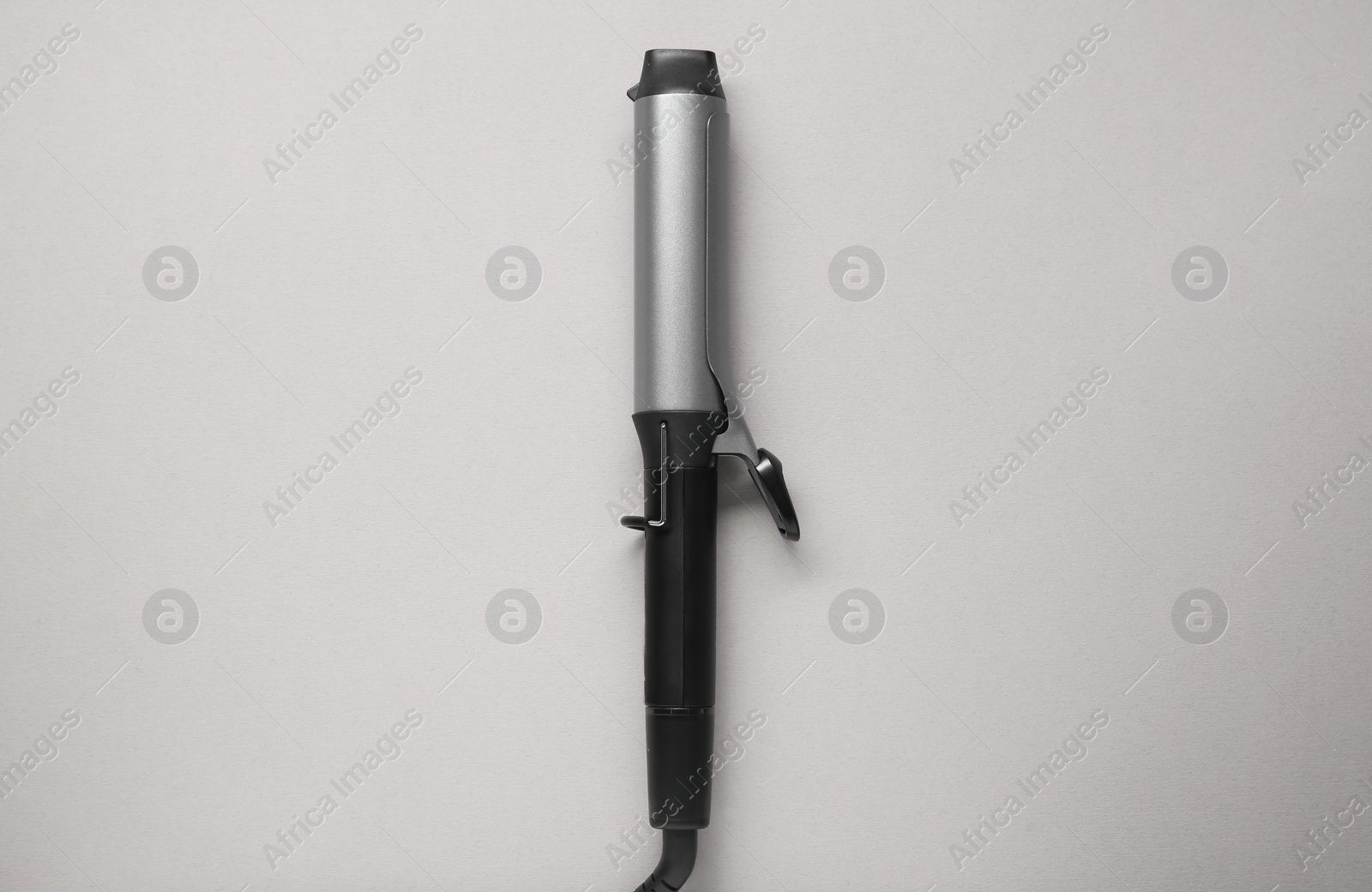 Photo of Hair curling iron on grey background, top view