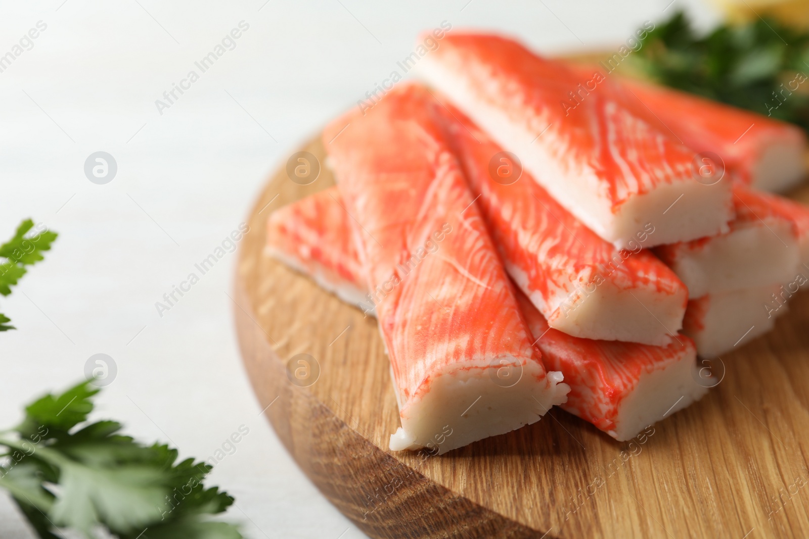 Photo of Fresh crab sticks on wooden cutting board, closeup