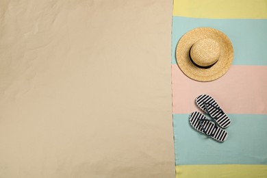 Photo of Beach towel, hat and flip flops on sand, top view. Space for text