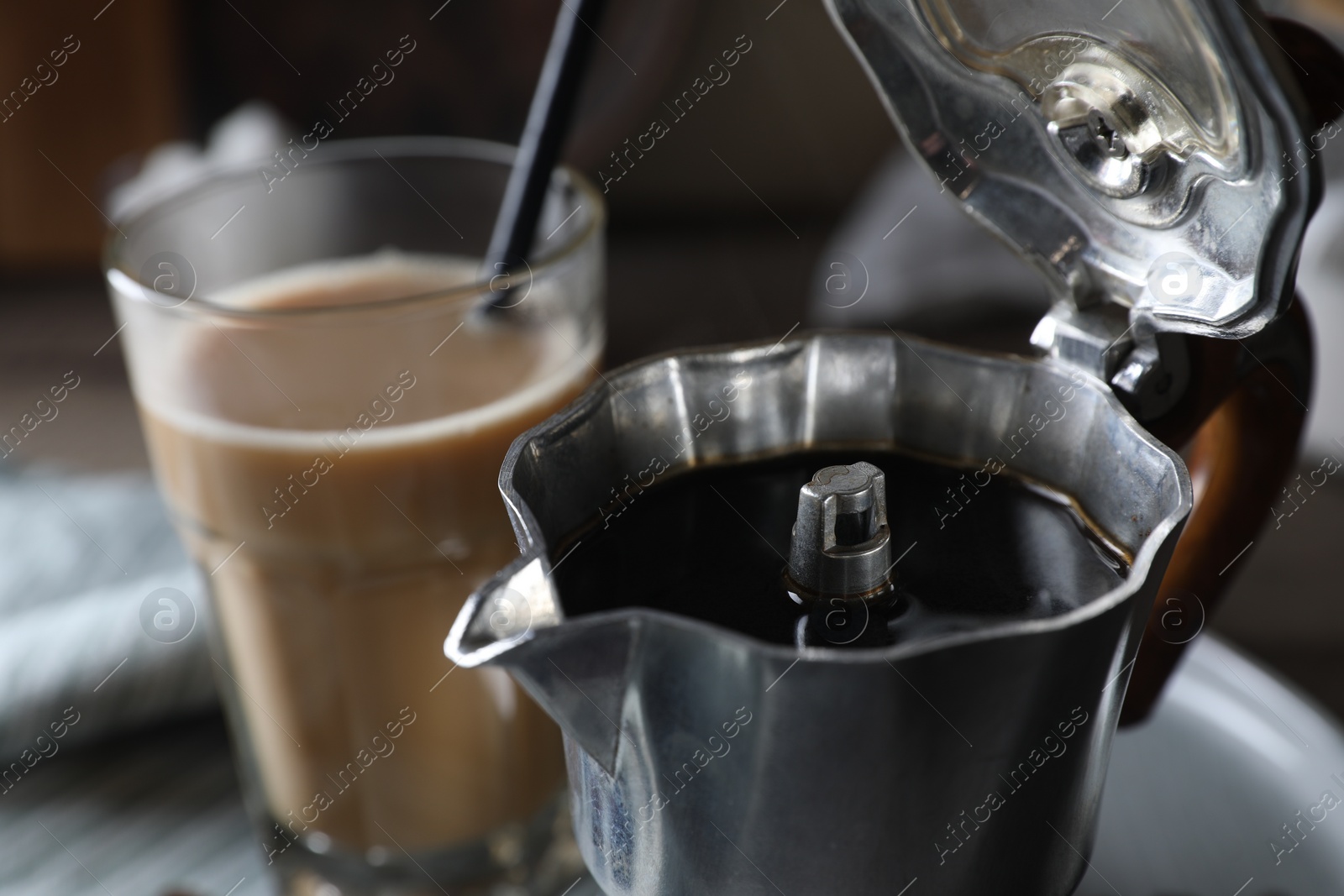 Photo of Brewed coffee in moka pot and glass of drink on table, closeup