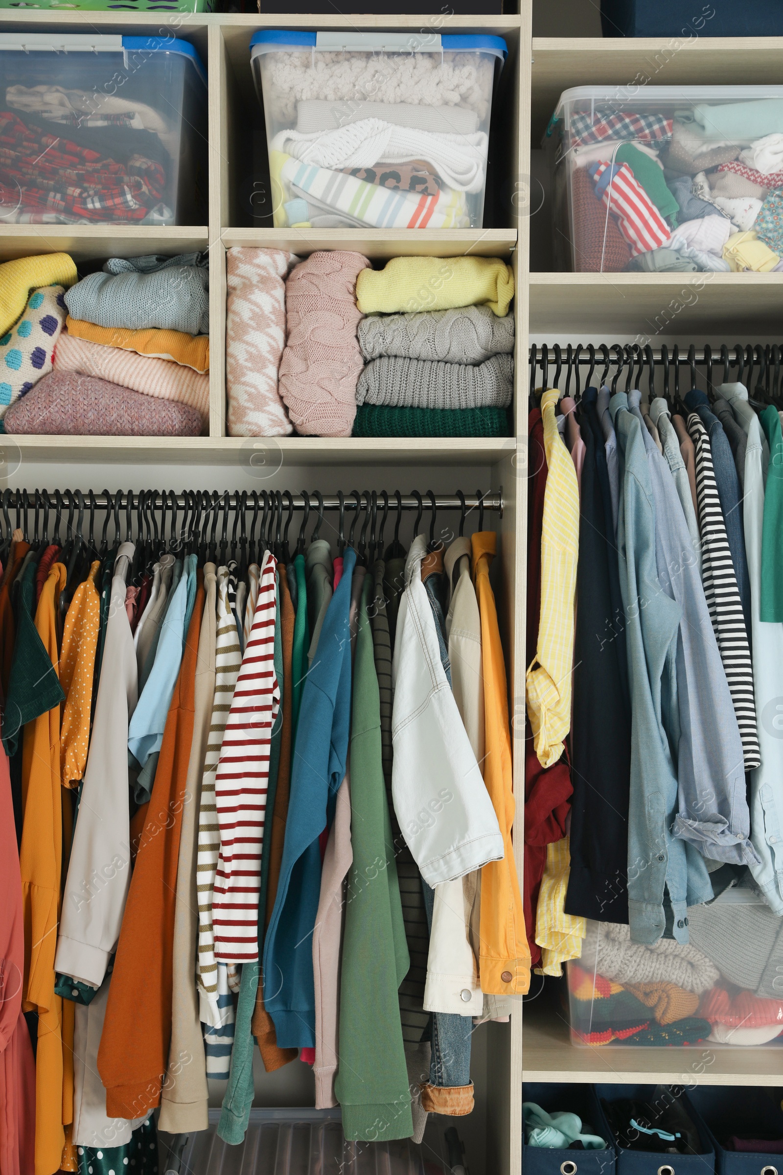 Photo of Wardrobe closet with different stylish clothes and home stuff. Fast fashion