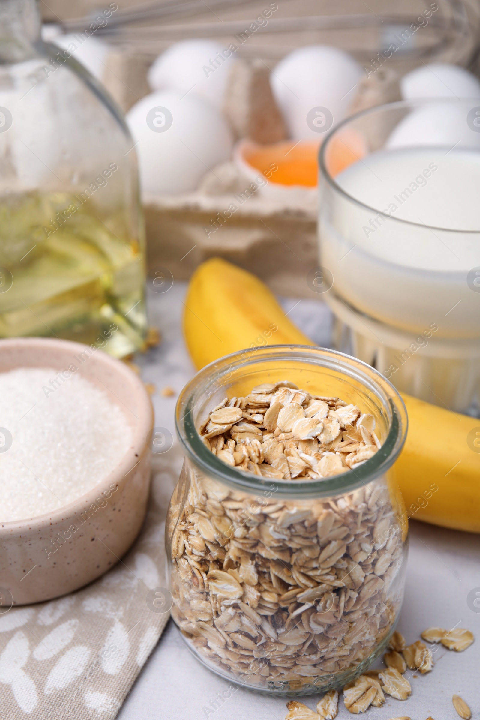 Photo of Different ingredients for cooking tasty oatmeal pancakes on white marble table