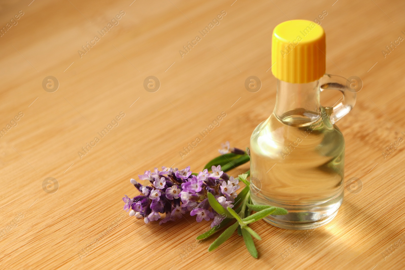 Photo of Bottle of natural essential oil and lavender flowers on wooden table, closeup. Space for text