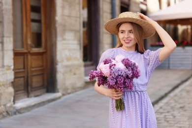 Photo of Beautiful woman with bouquet of spring flowers on city street, space for text