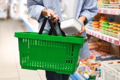 Woman with shopping basket in supermarket, closeup