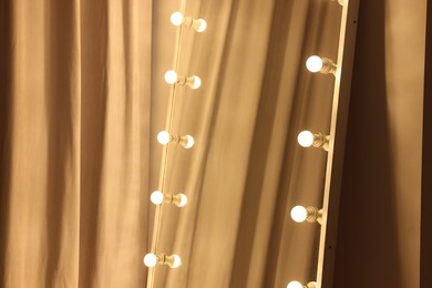 Modern mirror with light bulbs in makeup room, closeup