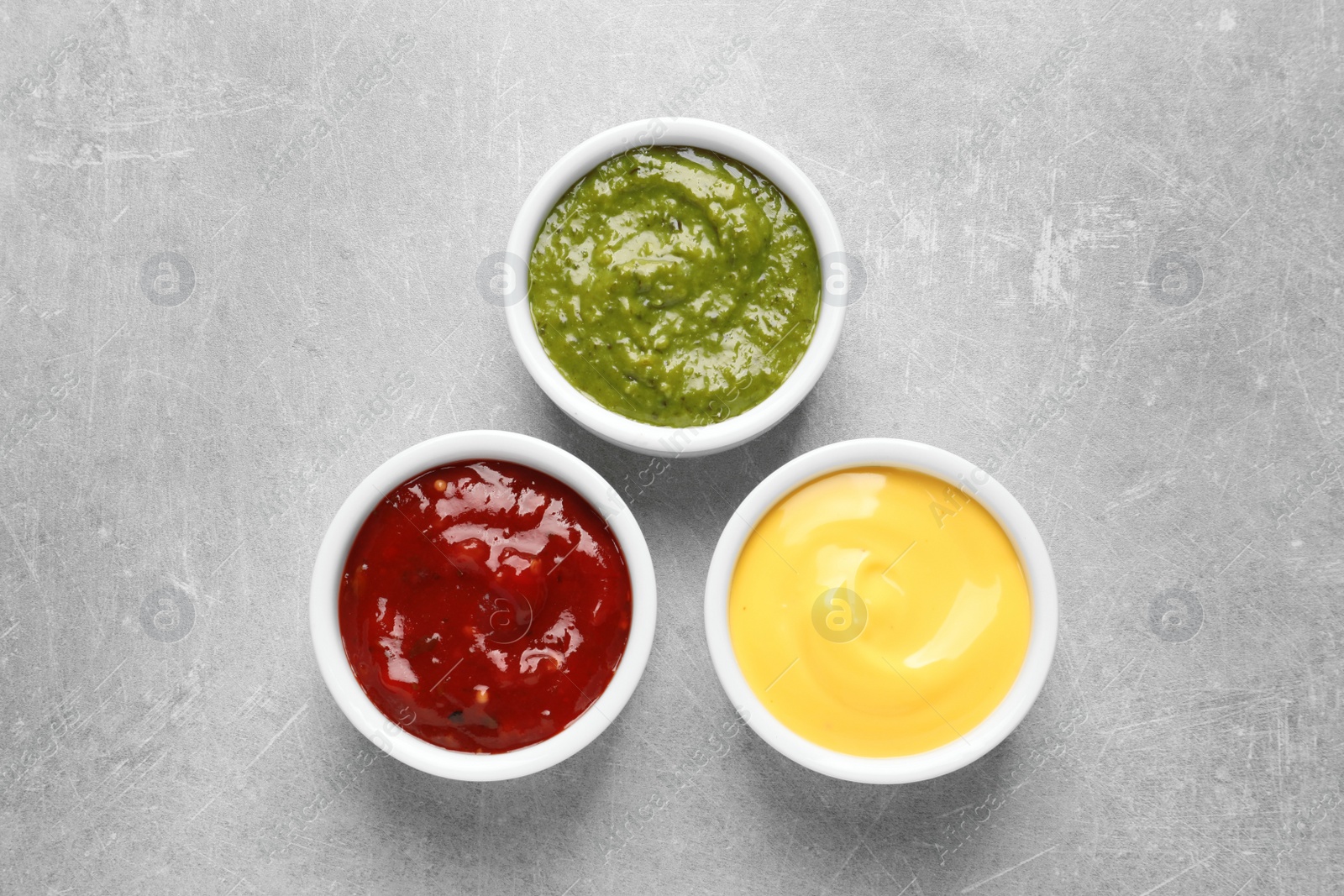 Photo of Set of different delicious sauces on grey table, top view