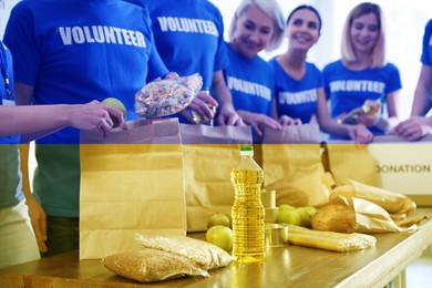 Image of Double exposure of volunteers packing products for refugees and Ukrainian flag, closeup. Help during war