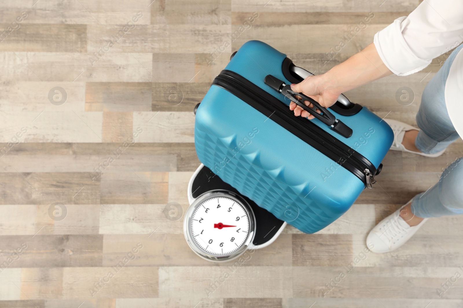 Photo of Woman weighing suitcase indoors, top view. Space for text