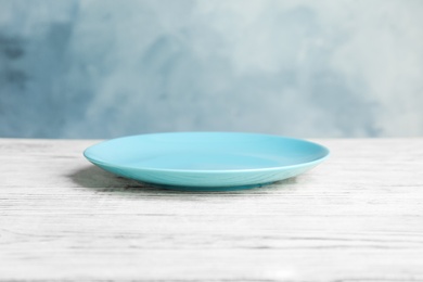 Photo of Empty light blue plate on white wooden table