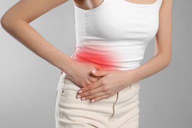 Woman suffering from appendicitis inflammation on grey background, closeup