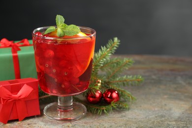 Aromatic Christmas Sangria in glass, gift boxes and festive decor on textured table, space for text