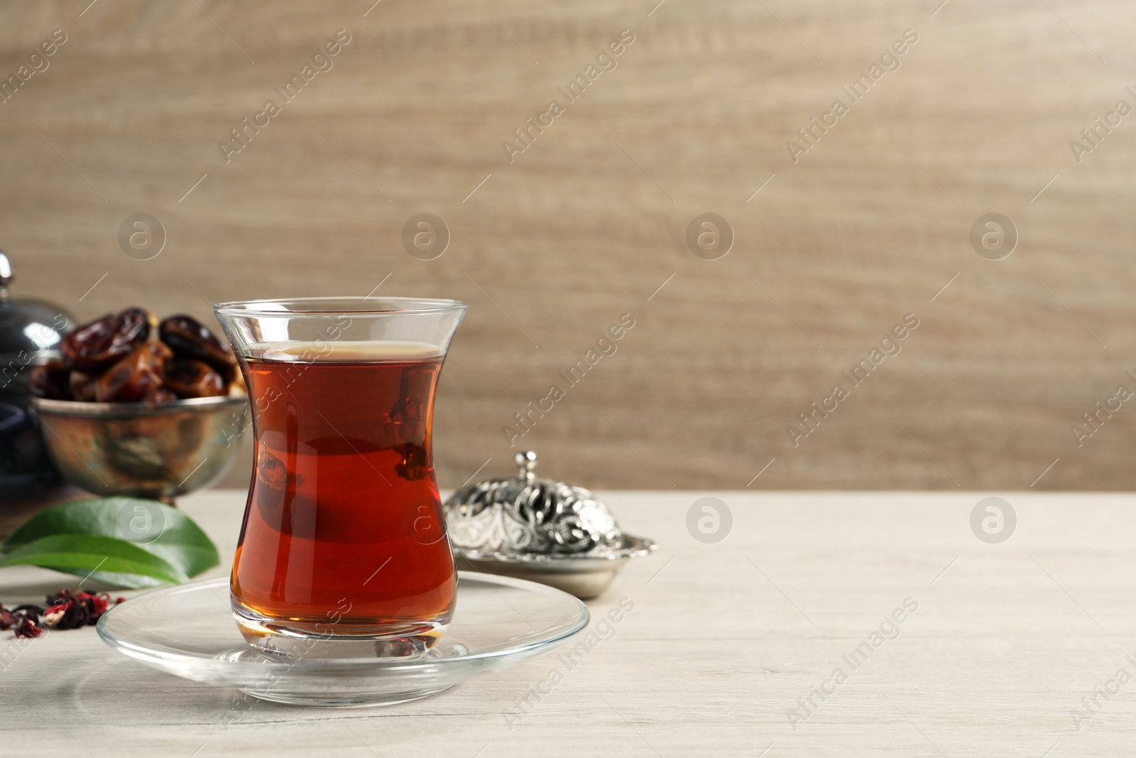 Photo of Tea in glass and vintage tea set on wooden table, space for text