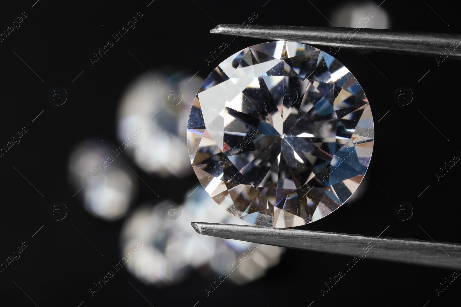 Photo of Tweezers with beautiful shiny diamond on black background, closeup