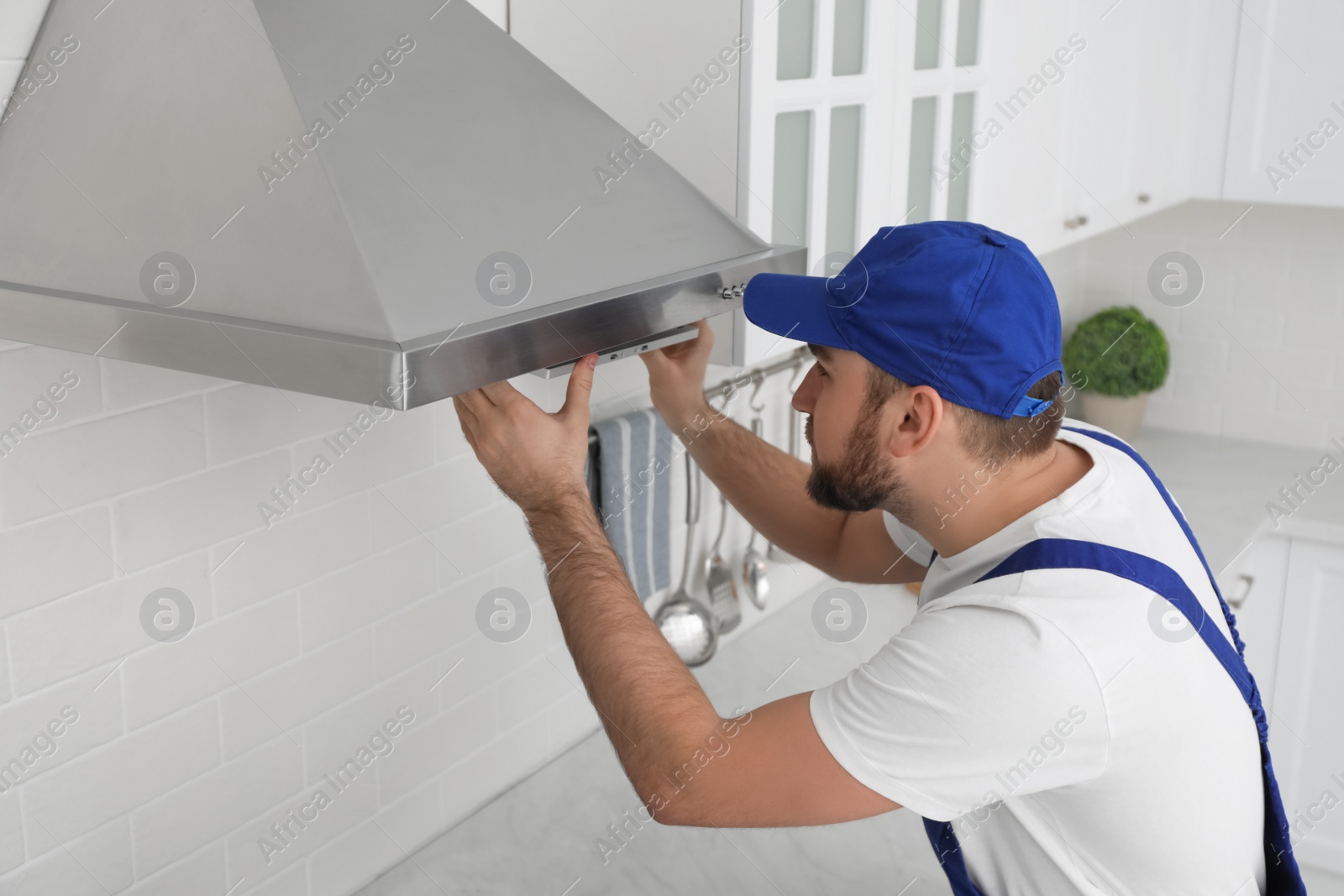 Photo of Worker repairing modern cooker hood in kitchen