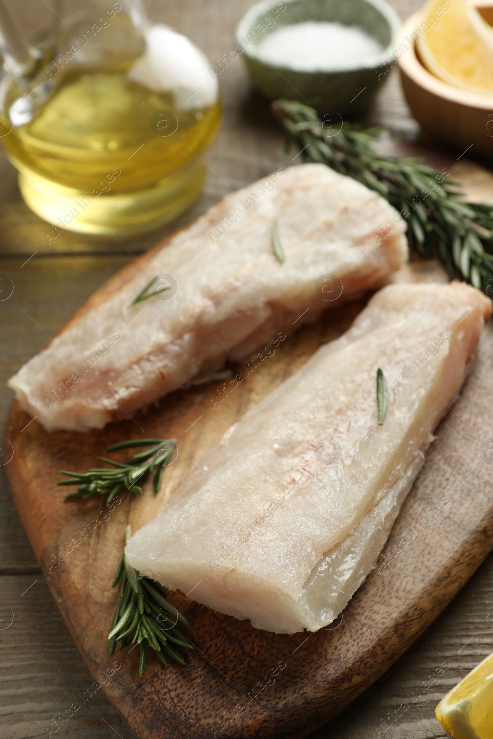 Photo of Fresh raw cod fillets and spices on wooden table, closeup