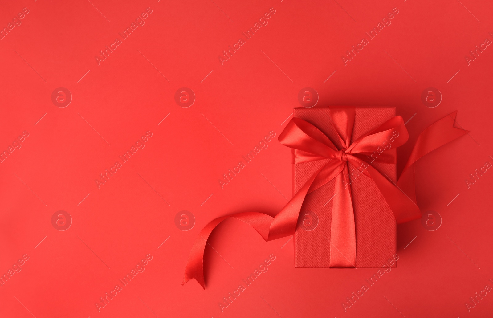 Photo of Beautiful gift box with bow on red background, top view. Space for text