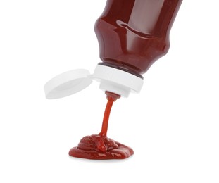 Photo of Pouring tasty red ketchup from bottle isolated on white