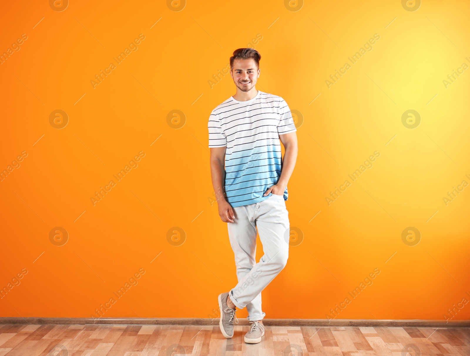 Photo of Young man in stylish jeans near color wall