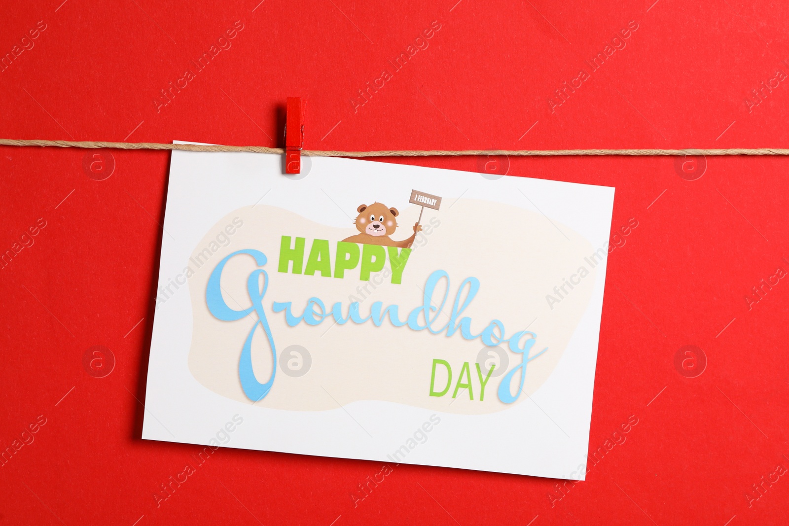 Photo of Happy Groundhog Day greeting card hanging on red background