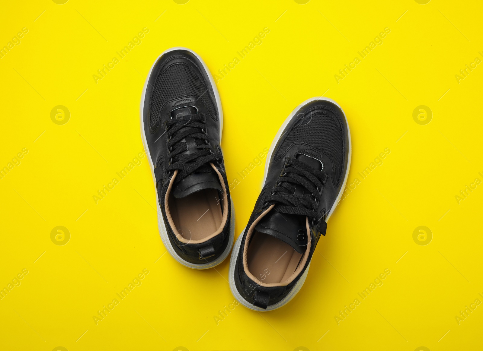 Photo of Pair of stylish shoes on yellow background, top view