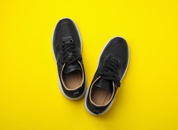 Photo of Pair of stylish shoes on yellow background, top view