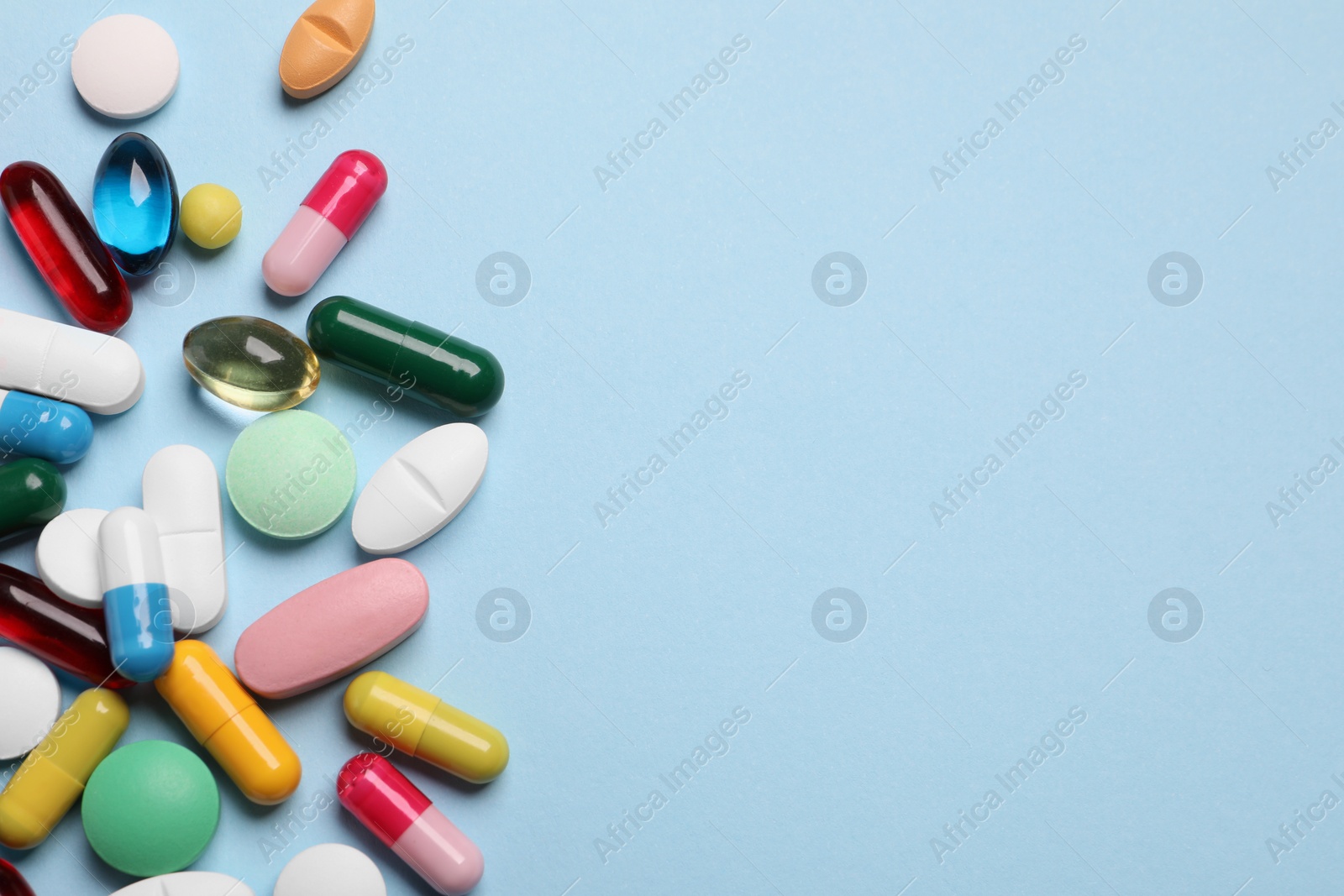 Photo of Many different pills on light blue background, flat lay. Space for text