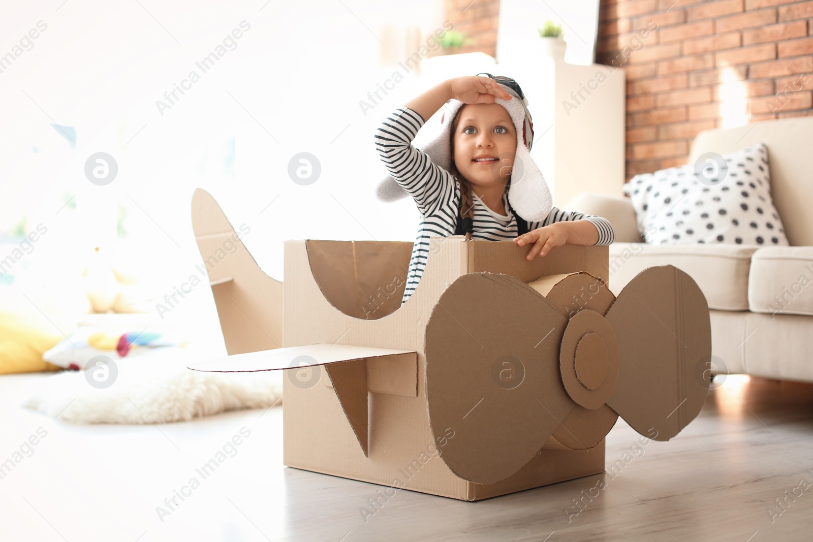 Photo of Adorable little child playing with cardboard plane at home
