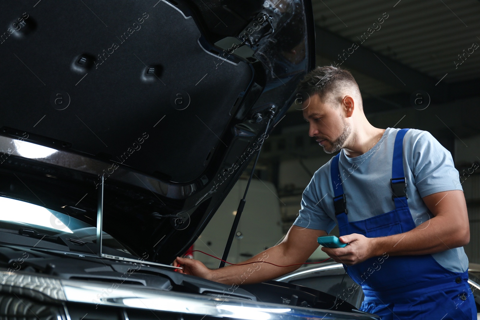 Photo of Mechanic with laptop doing car diagnostic at automobile repair shop