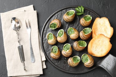 Photo of Delicious cooked snails served on grey textured table, flat lay