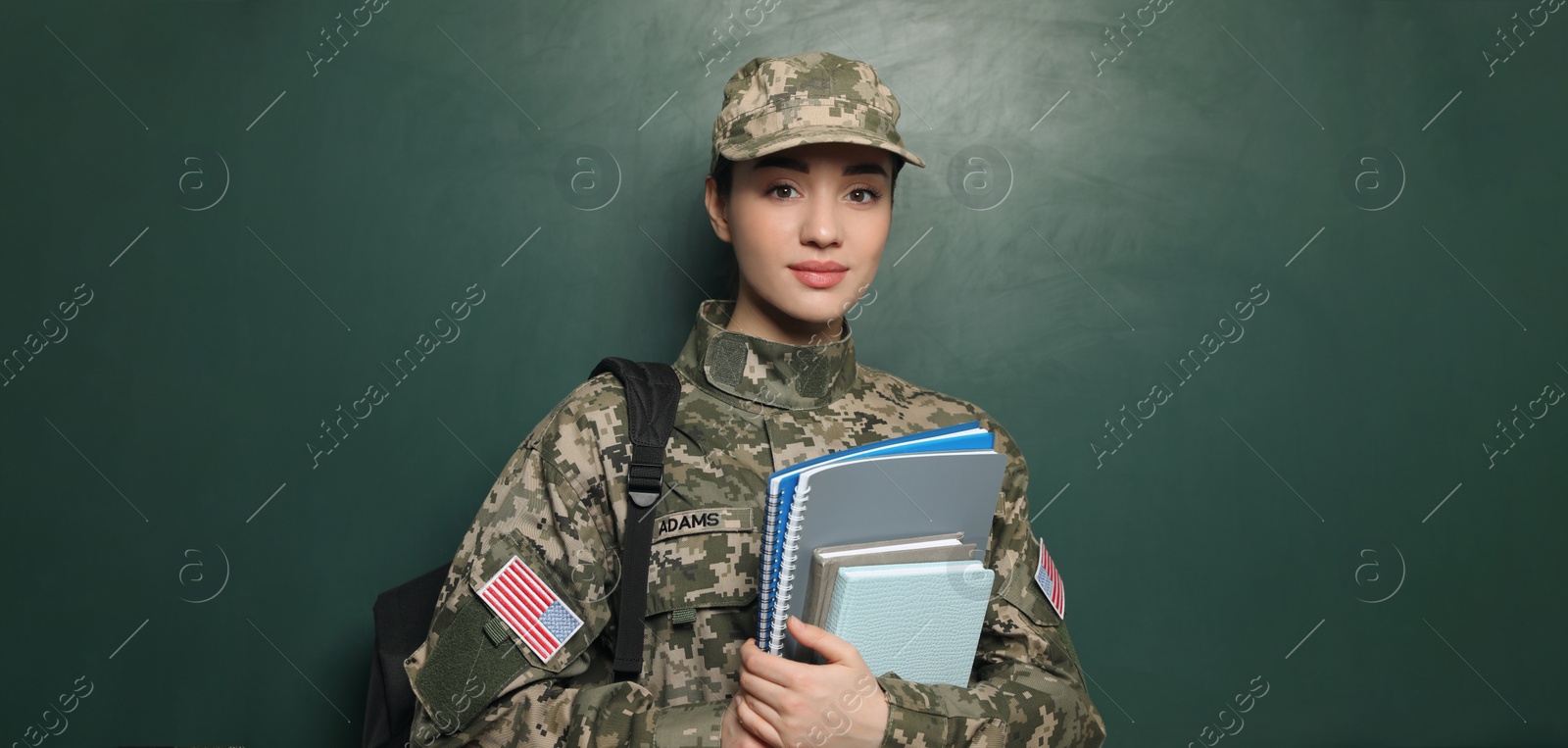 Image of Military education. Cadet with backpack and notebooks near green chalkboard