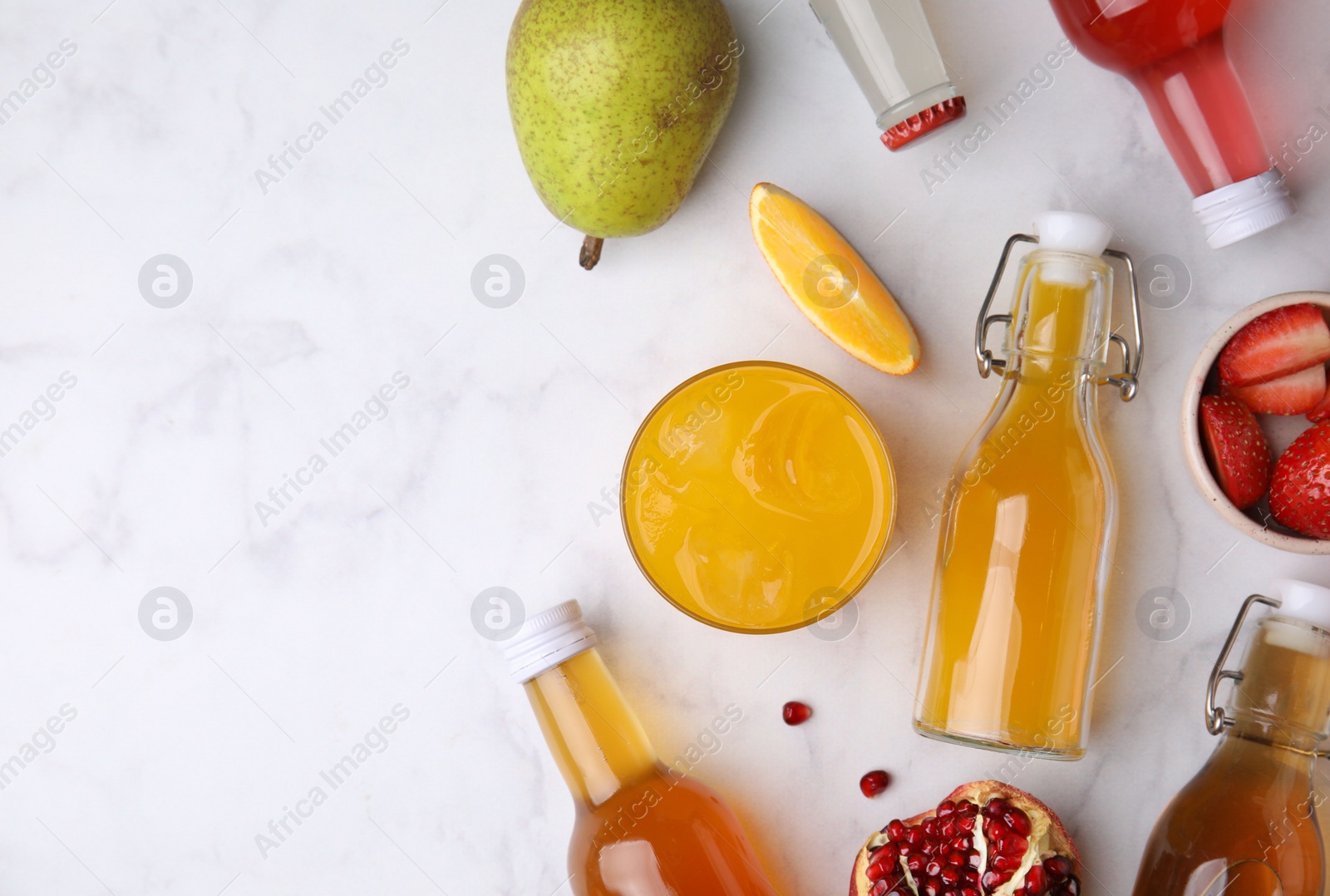 Photo of Tasty kombucha in bottles, glass and fresh fruits on white marble table, flat lay. Space for text