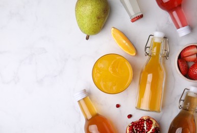 Tasty kombucha in bottles, glass and fresh fruits on white marble table, flat lay. Space for text