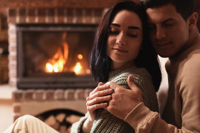 Photo of Happy couple resting near fireplace indoors. Winter vacation