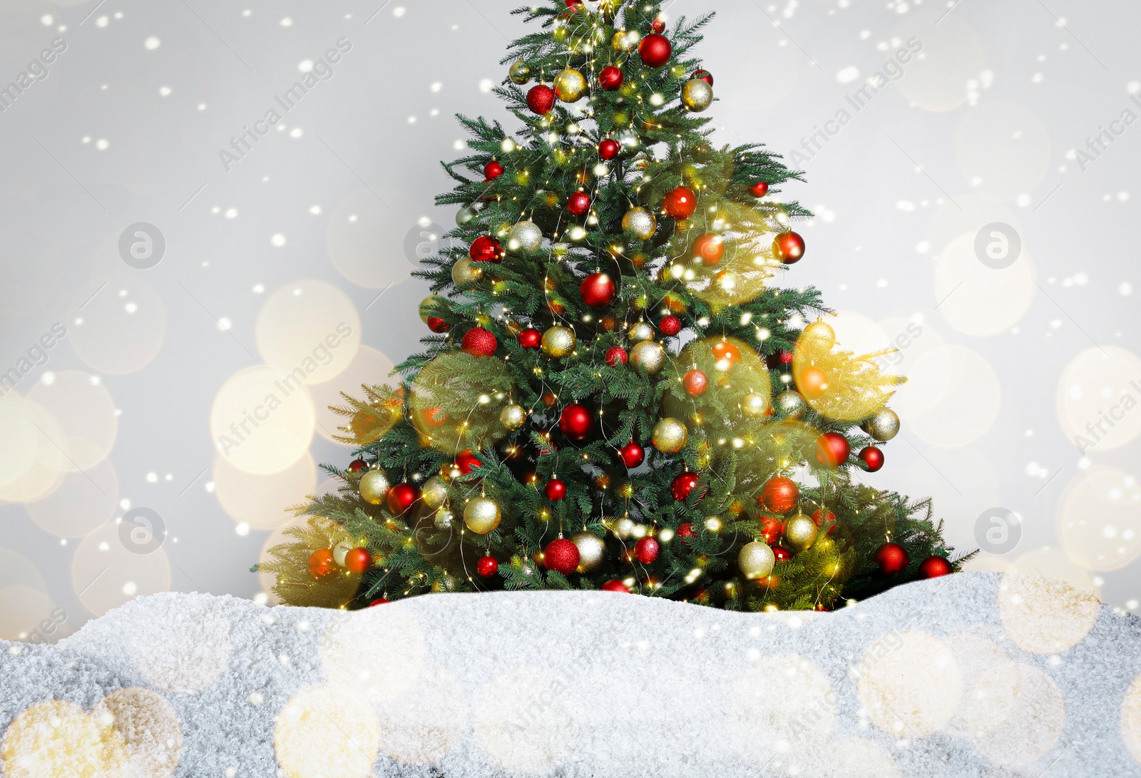 Image of Beautifully decorated Christmas tree and snow on light background. Bokeh effect