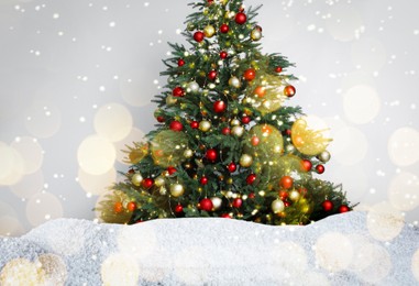 Image of Beautifully decorated Christmas tree and snow on light background. Bokeh effect