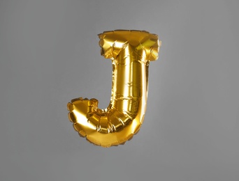 Golden letter J balloon on grey background