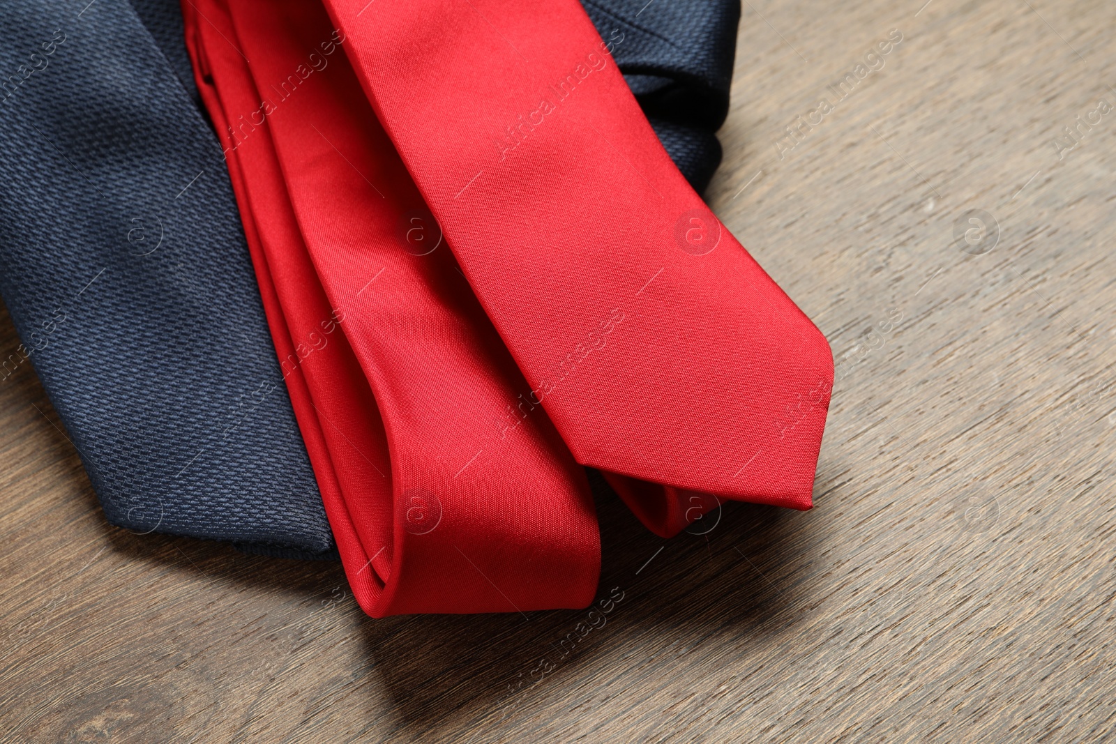 Photo of Red and blue neckties on wooden table, closeup