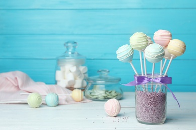 Photo of Sweet cake pops on white wooden table against light blue background. Space for text