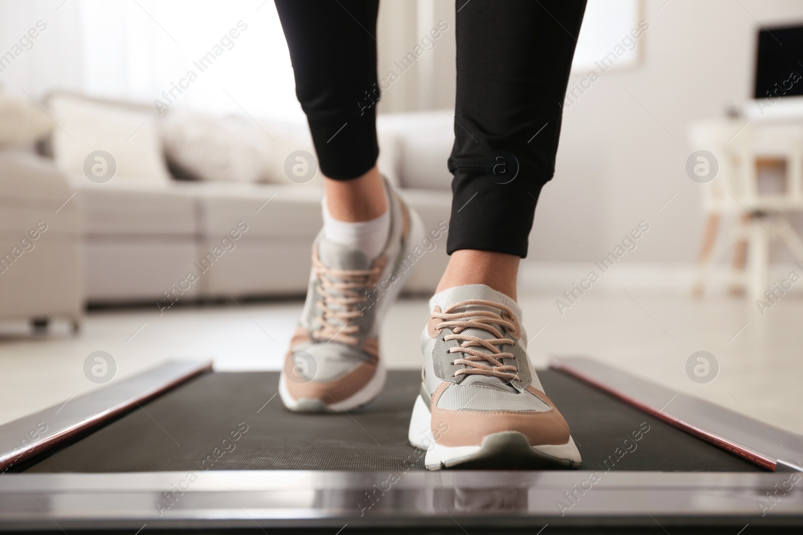 Photo of Woman training on walking treadmill at home, closeup