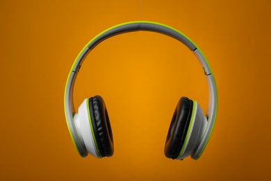 Photo of Wireless headphones with earmuffs on color background