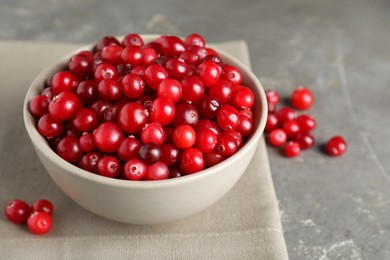 Photo of Cranberries in bowl on light grey table, closeup