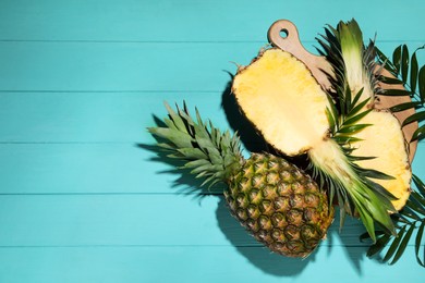 Photo of Whole and cut ripe pineapples on light blue wooden table, flat lay. Space for text
