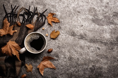 Flat lay composition with cup of hot drink and autumn leaves on grey table, space for text. Cozy atmosphere