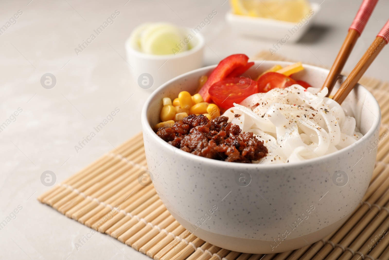 Photo of Bowl with rice noodles, meat and vegetables on table