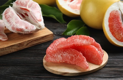 Photo of Peeled pomelo slices on black wooden table