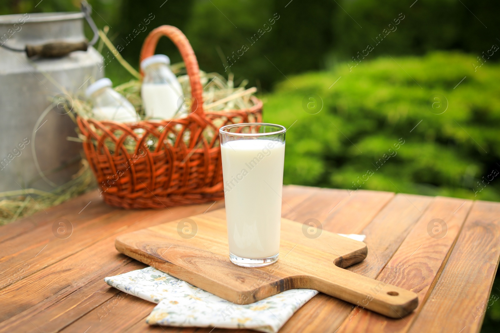 Photo of Tasty fresh milk in glass on wooden table outdoors